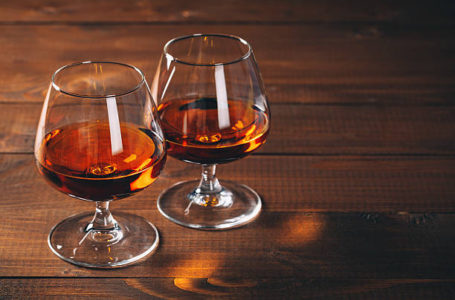 Two glasses of cognac on the wooden table.